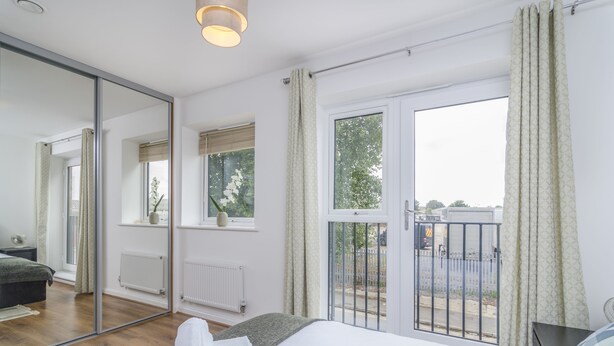 Ein modernes Schlafzimmer mit einem großen Bett, einem Spiegel, einem Fenster mit Blick auf die Straße und einer Heizung.