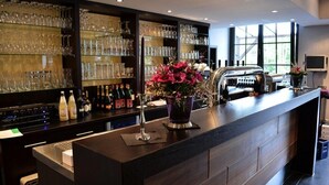 Una zona de bar con estantes llenos de vasos y botellas, una barra con un florero y una parrilla.
