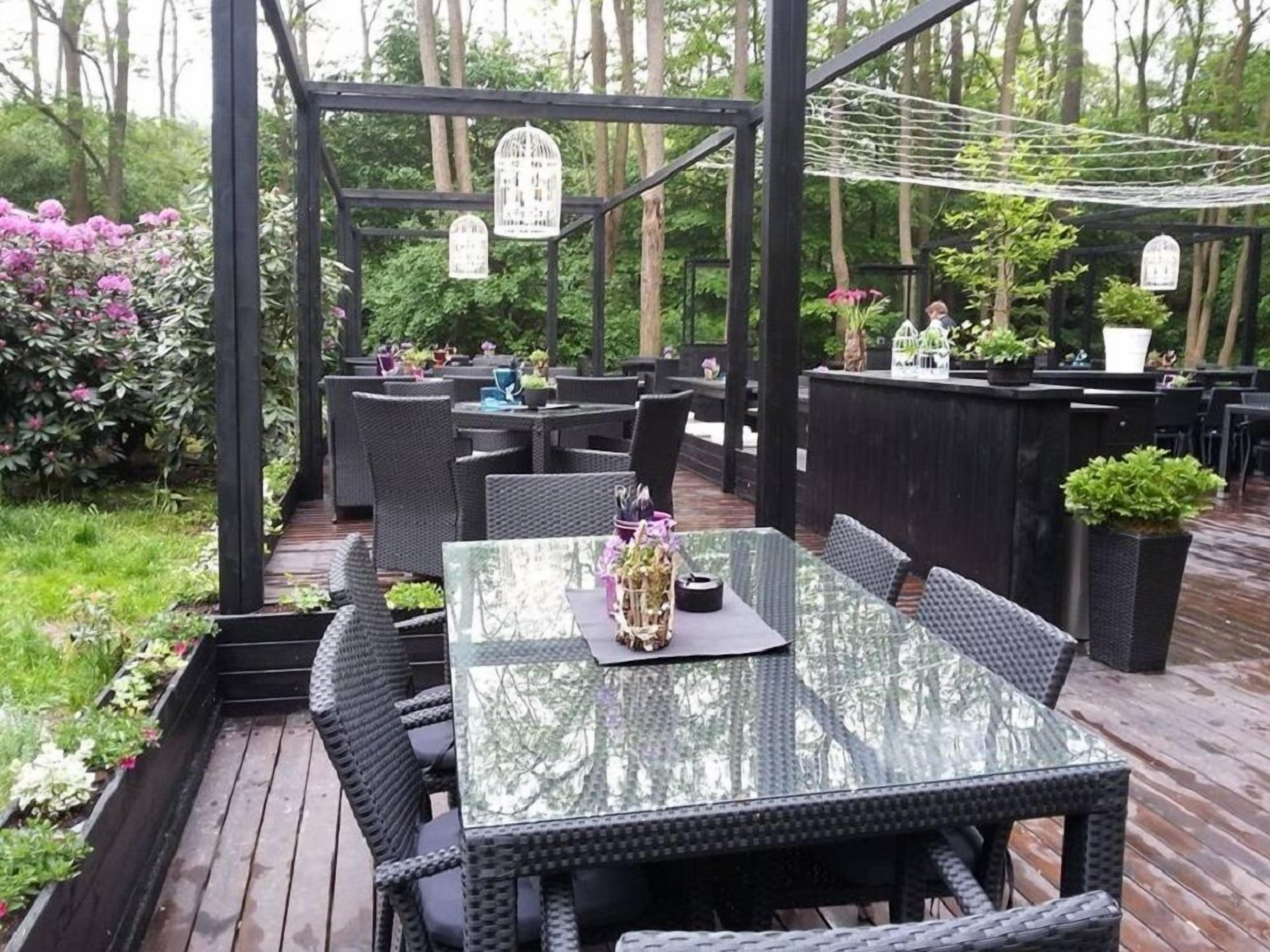 An outdoor patio with wicker furniture, a glass-top table, and a wooden deck.