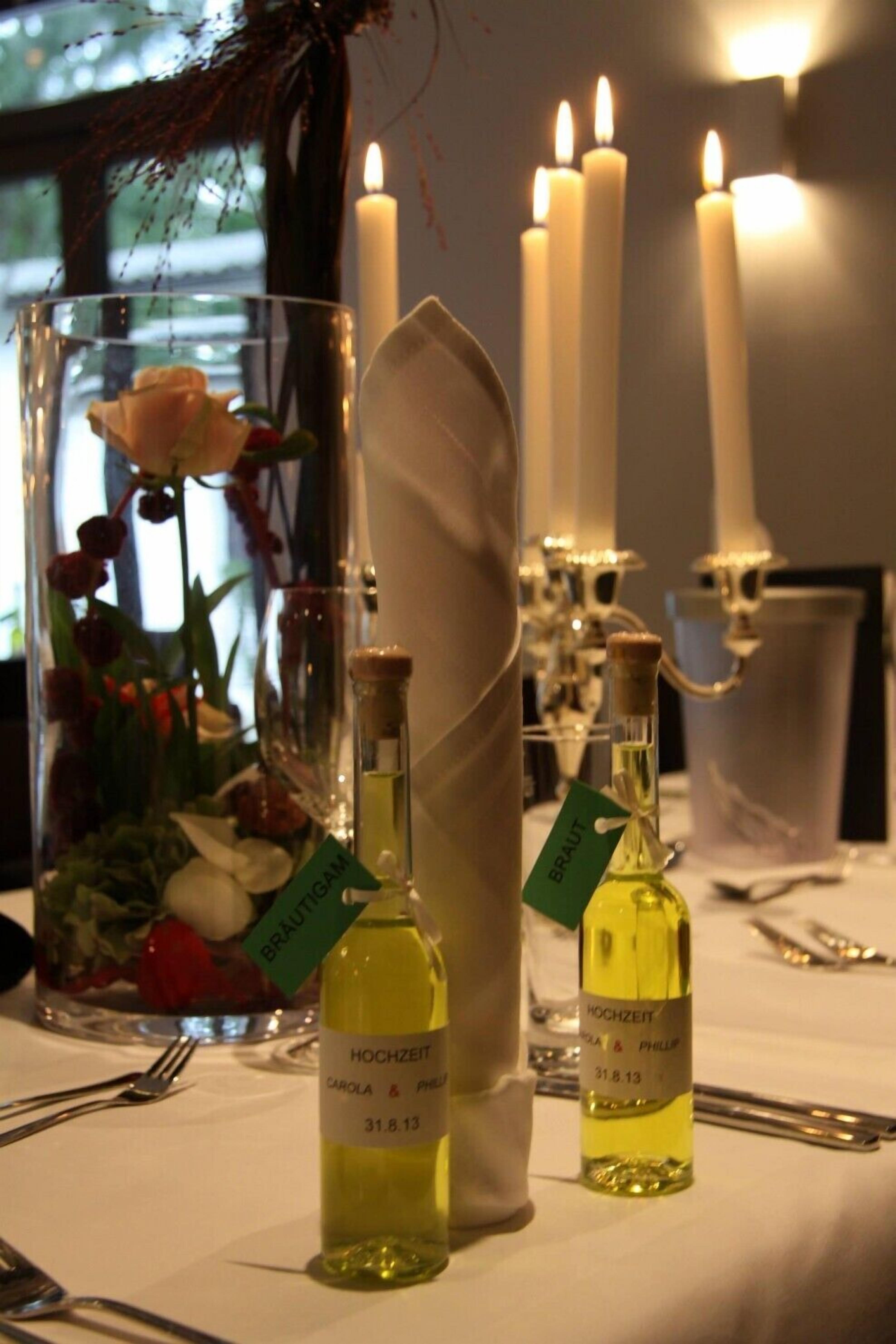 Ein Tisch, gedeckt mit Kerzen, einer Glasvase mit Blumen und zwei Parfumflaschen.