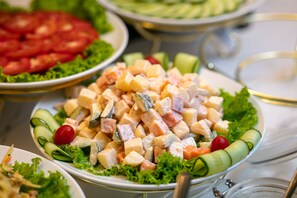A buffet with various dishes including a salad with cucumbers and tomatoes, a fruit salad, and a seafood salad. - Shining Central Hotel & Spa (Hanoi)