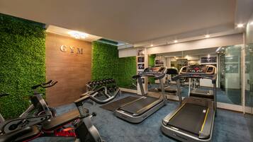 A gym with treadmills, stationary bikes, and dumbbells.