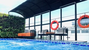 A pool area with a covered seating area, a lifebuoy, and a view of the city through large windows. - Shining Central Hotel & Spa (Hanoi)