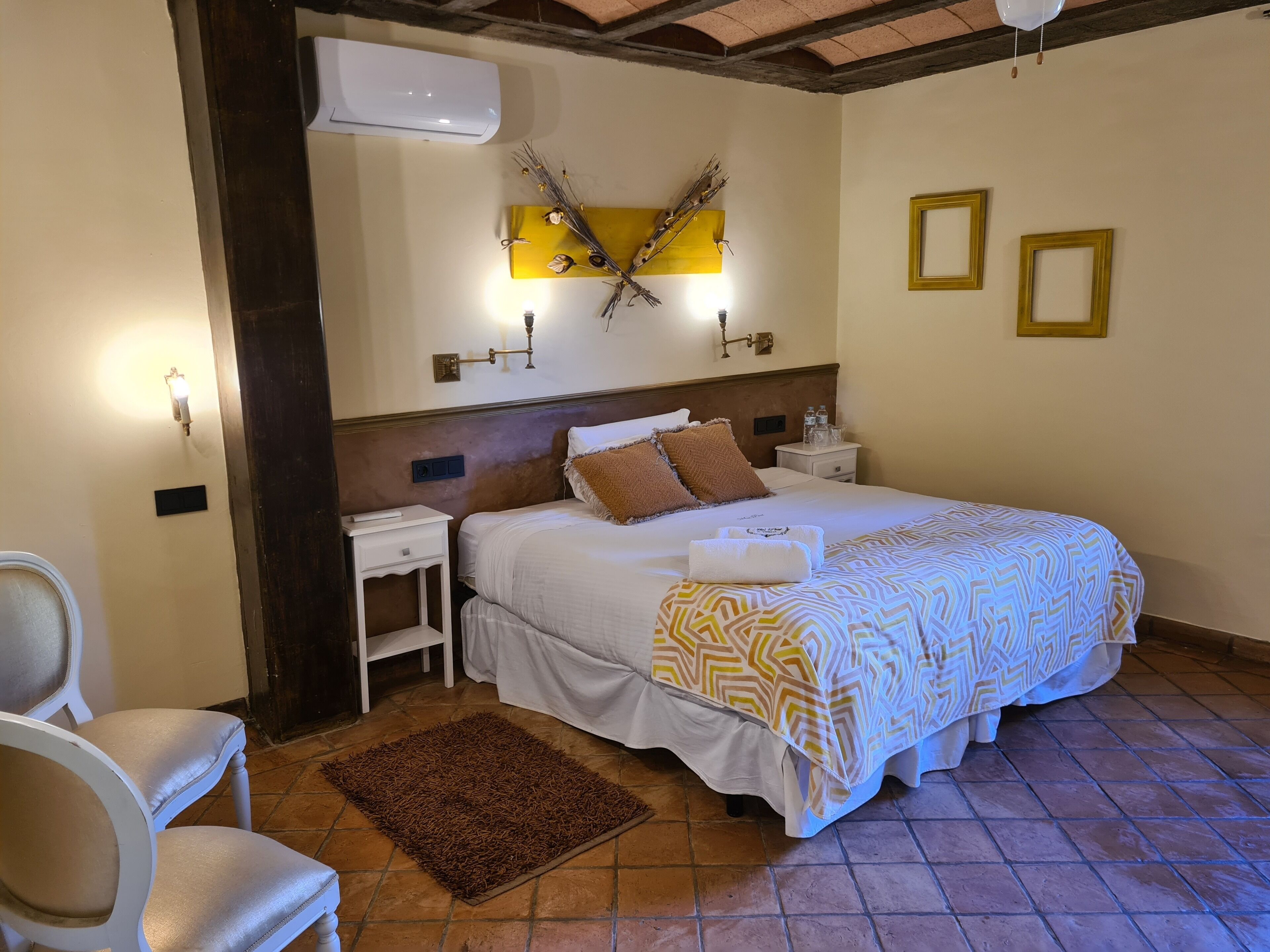 A hotel room with a bed, two bedside tables, a chair, a rug, and wall-mounted decor.