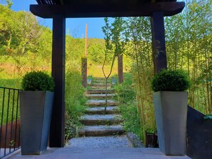 A stone staircase leading up to a wooden pergola with a view of a bamboo forest. - Hotel Rural & Spa Mas Prat (La Vall de Bianya)