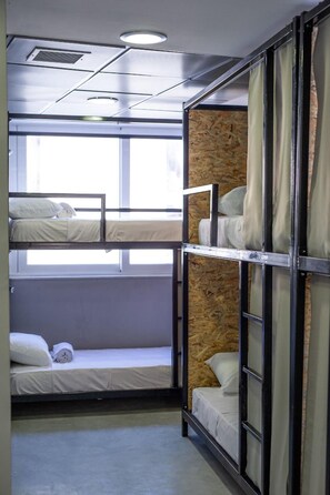 Ein Schlafraum mit Etagenbetten, einem Fenster, einer Heizung und einer Holzwand.