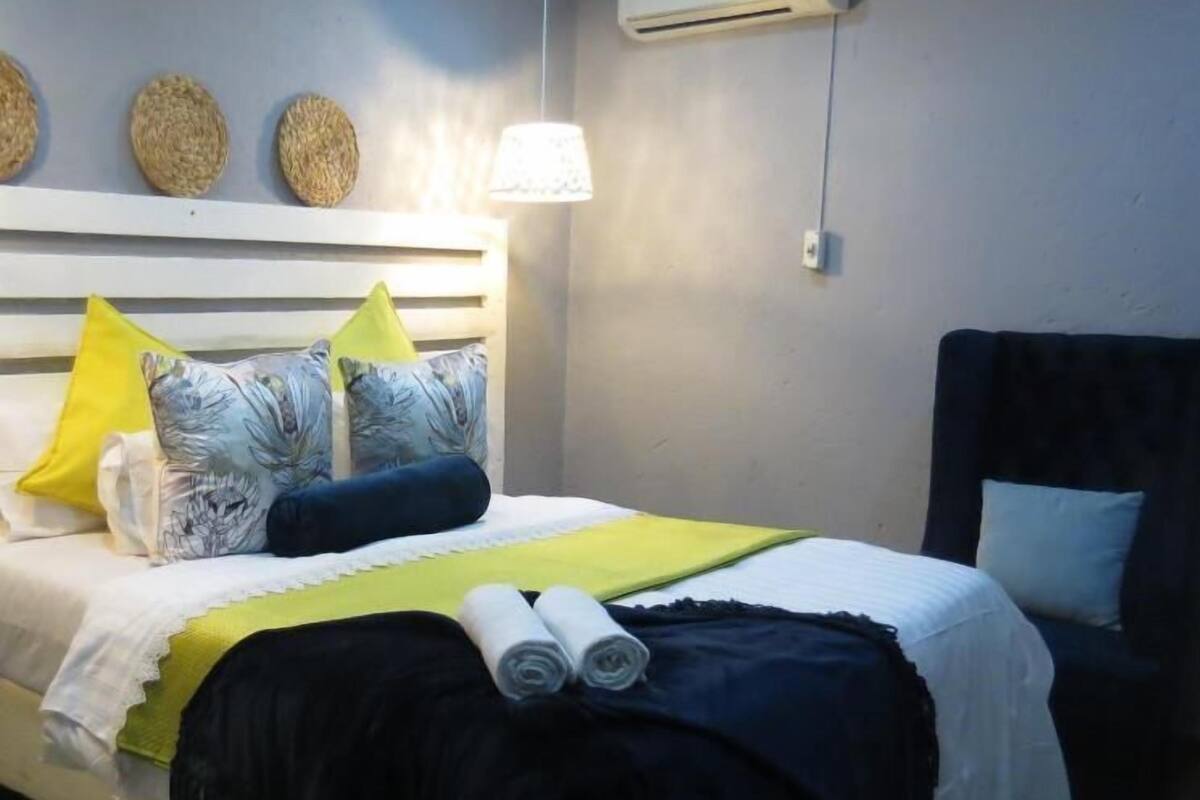A neatly made bed with a white headboard, multiple pillows, and a yellow throw blanket.