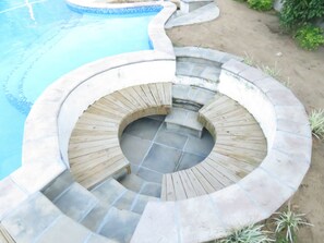 A circular stone staircase leading to a hot tub area with a pool in the background. - Nkanhe Lodge (Ponta d'Ouro)