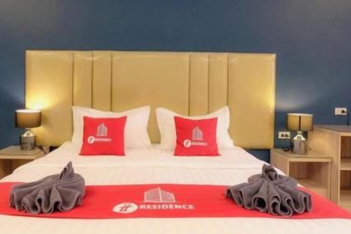 Een hotelkamer met een bed, twee kussens, een rode deken en een handdoek.