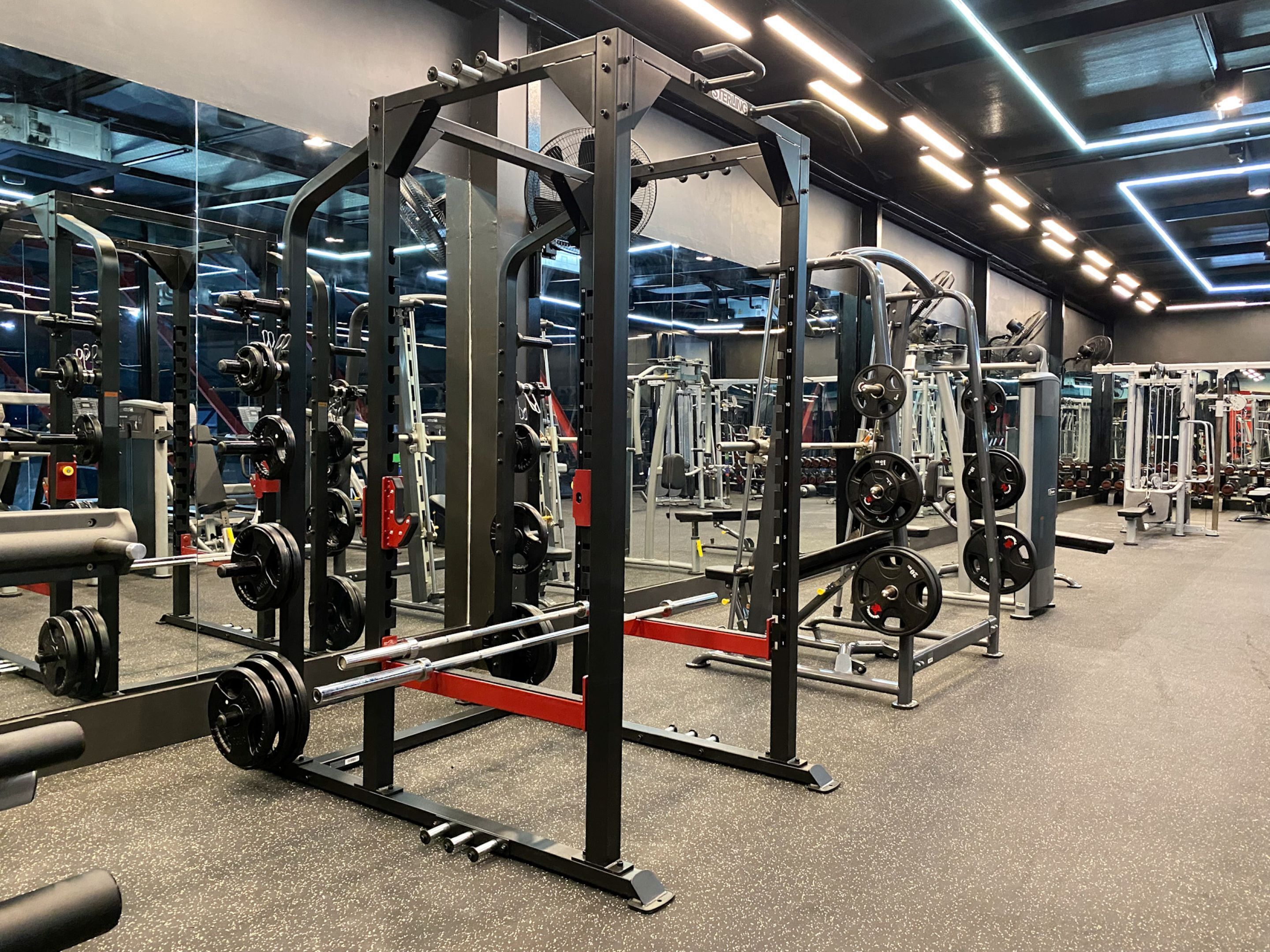 A gym with various weightlifting equipment, including squat racks and benches.