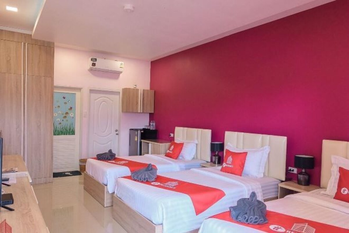 A hotel room with two beds, a desk, a wardrobe, and a door with a decorative painting.