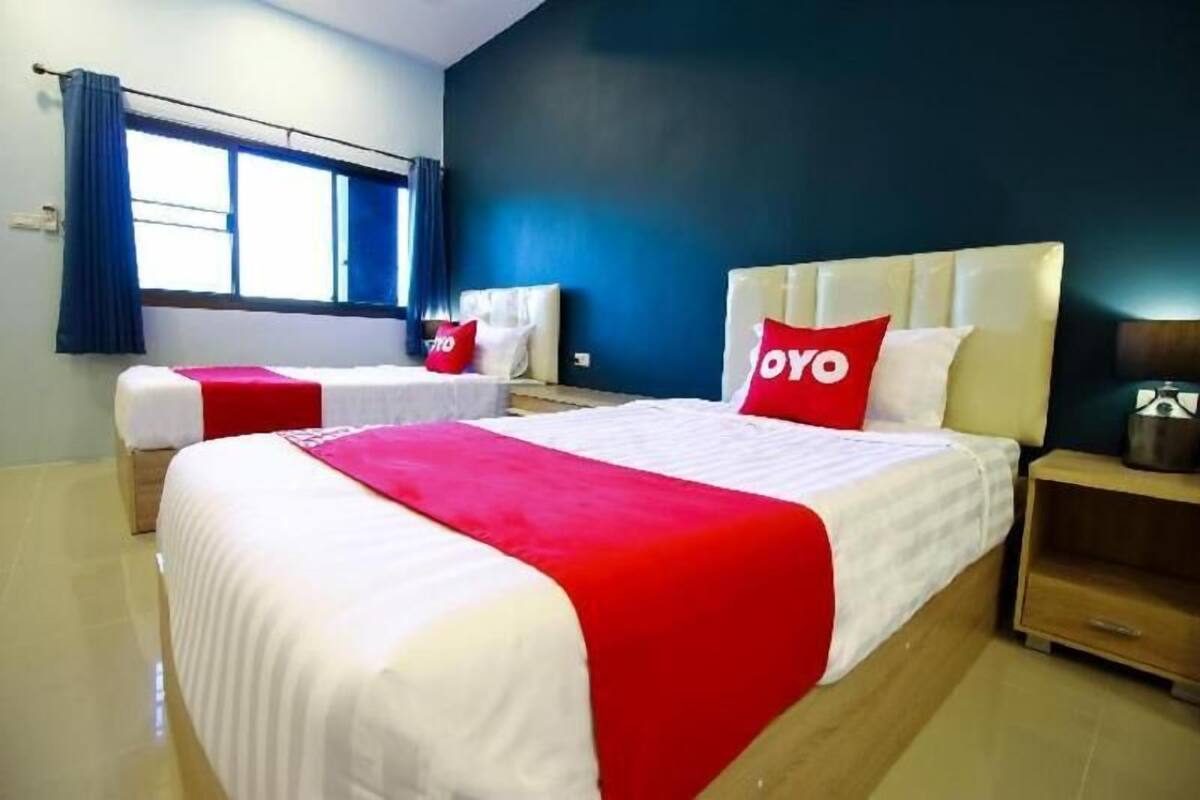 A hotel room with two beds, a large window, a nightstand, and a dark blue wall.