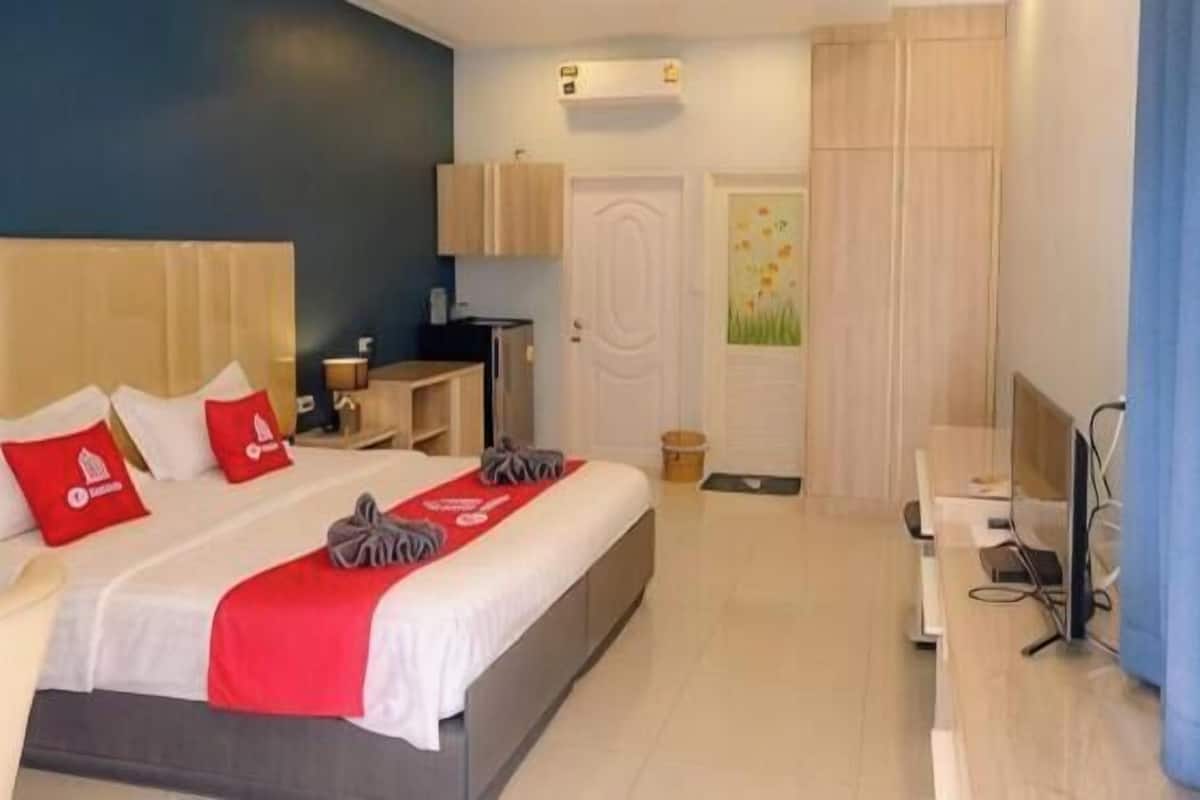 Une chambre d’hôtel avec un lit, un bureau, une chaise, une télévision et une fenêtre.