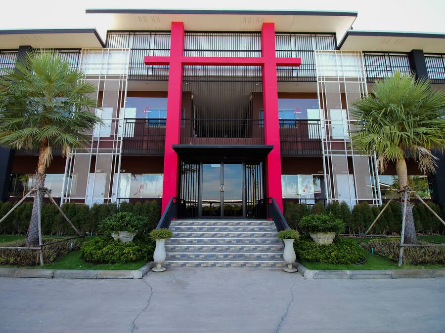Un edificio moderno con entrada roja, una escalera y dos palmeras.