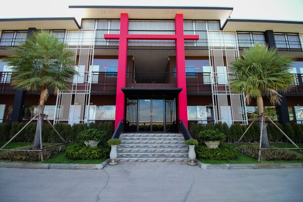 A modern building with a red entrance, a staircase, and two palm trees. - TT Residence (Bang Nam Prieo)