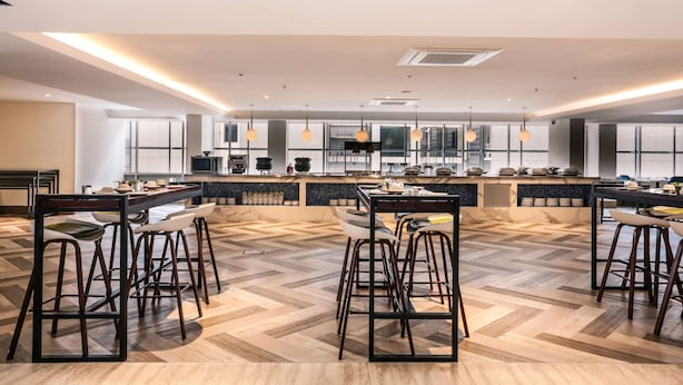 Una cocina moderna con una isla central, taburetes de bar y un suelo con diseño de espiga.