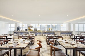 A spacious dining area with multiple tables and chairs, a kitchen in the background, and large windows allowing natural light. - Days Hotel and Suites Fraser Business Park KL (Kuala Lumpur)