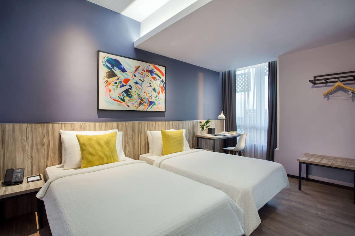Una habitación de hotel con dos camas, un escritorio, una silla y un banco.