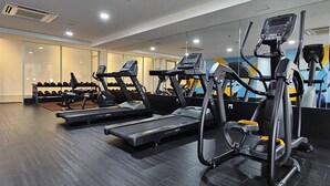 Un gimnasio moderno con cintas de correr, una máquina de remo y mancuernas.