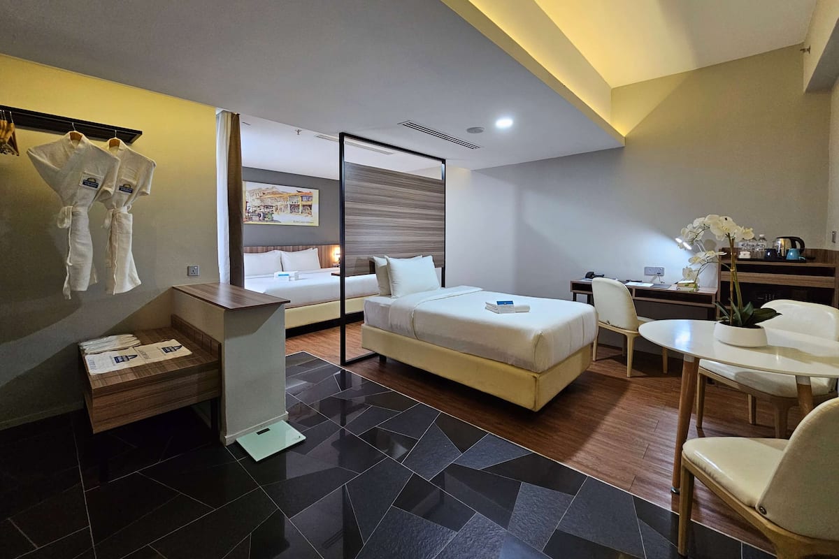 Una habitación de hotel moderna con una cama, un escritorio, una silla y una pequeña mesa. Hay un banco de madera y una planta en el escritorio.