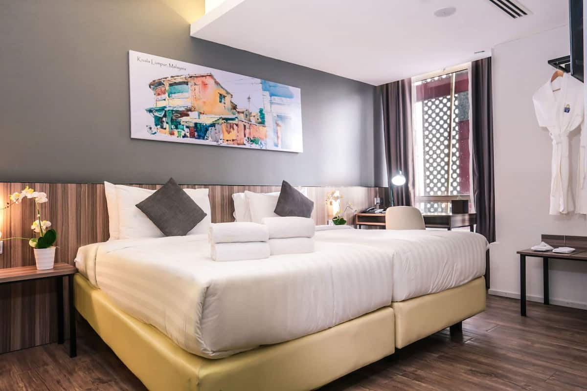 Una habitación de hotel moderna con una cama grande, un escritorio, una silla y una ventana con cortinas.