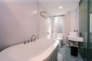 A modern bathroom with a large bathtub, a toilet, and a sink. - Days Hotel and Suites Fraser Business Park KL (Kuala Lumpur)