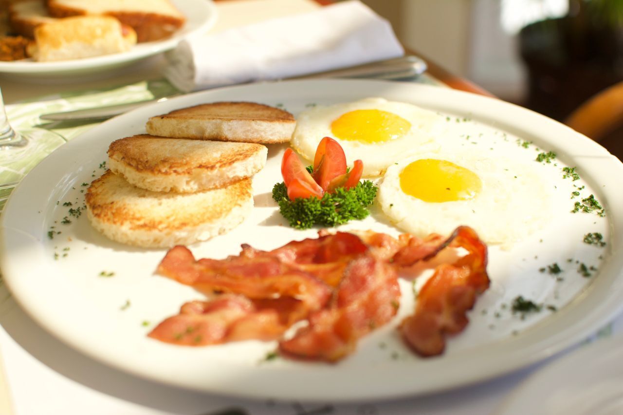 A breakfast plate with eggs, bacon, and toast.