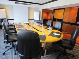 A conference room with a long table, black chairs, water bottles, and a whiteboard.