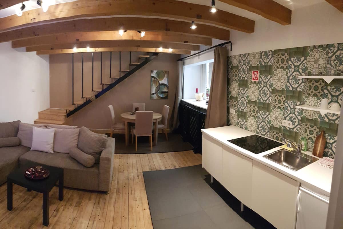A cozy living area with a sofa, a small table, and a staircase leading to a dining area.
