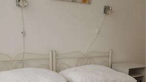 Cama bem arrumada com roupa de cama branca e toalha azul.