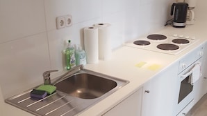 Uma cozinha moderna com uma pia de aço inoxidável, máquina de lavar louça, fogão e cafeteira.