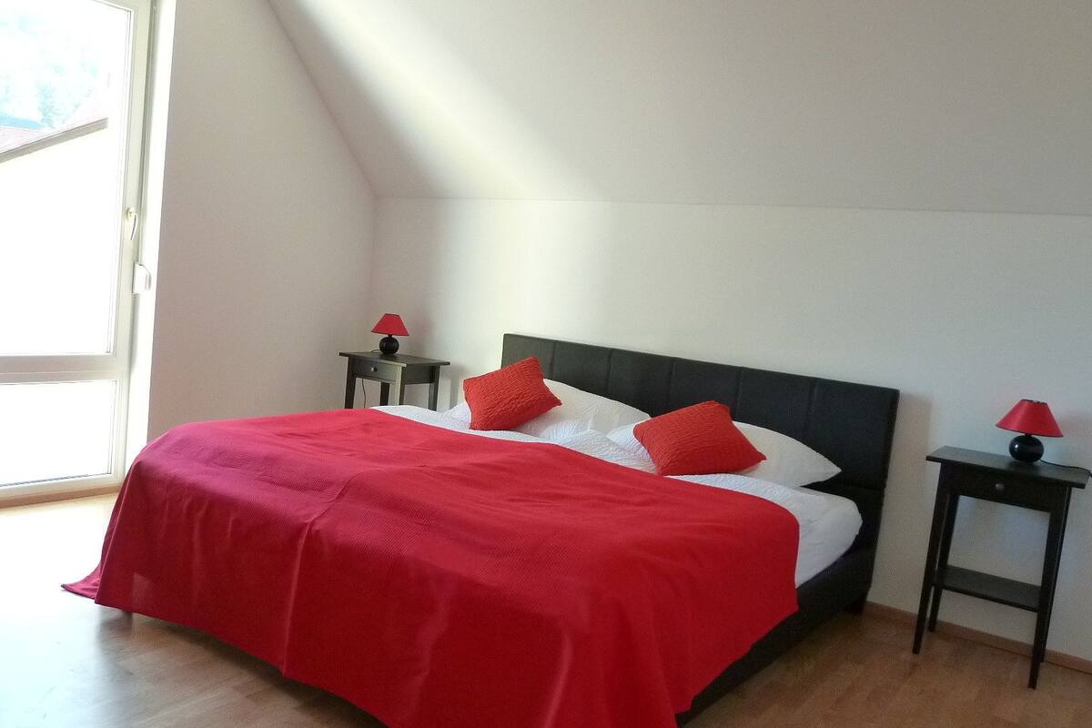A bedroom with a bed, two nightstands, and a window.