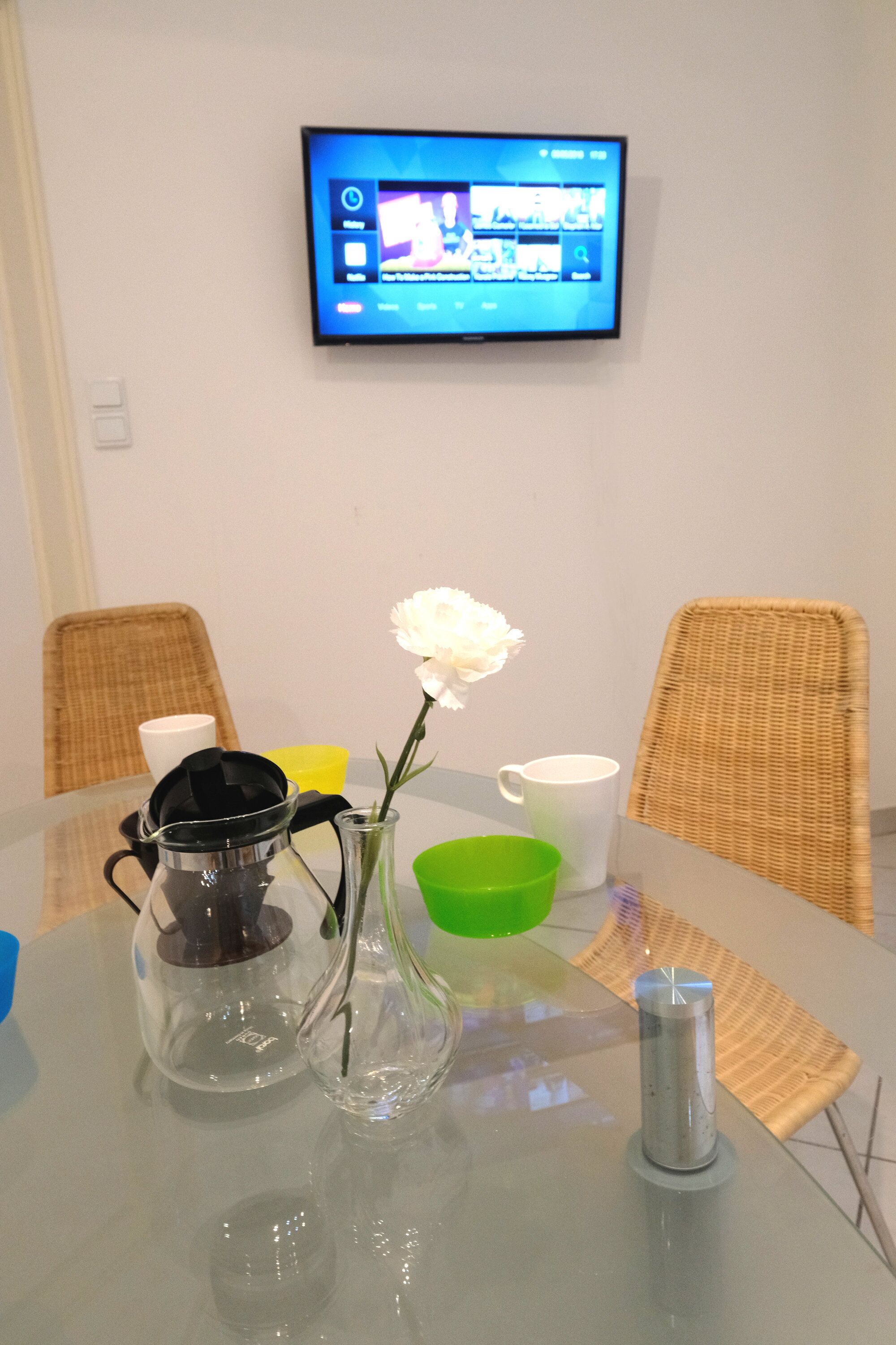 A conference table with a coffee pot, a vase with a flower, and a mug.