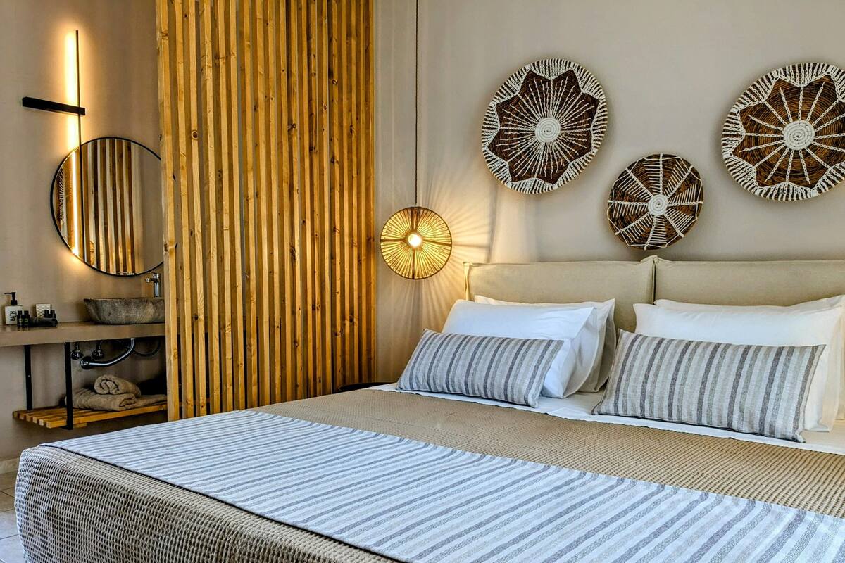 Ein modernes Schlafzimmer mit einem großen Bett, einer Wand aus Holzlatten, einem runden Spiegel und drei Wanddekorationen.