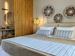 A modern bedroom with a large bed, a wooden slat wall, a round mirror, and three decorative wall pieces. - Villa Karina - Near Achladies Beach (Skiathos)