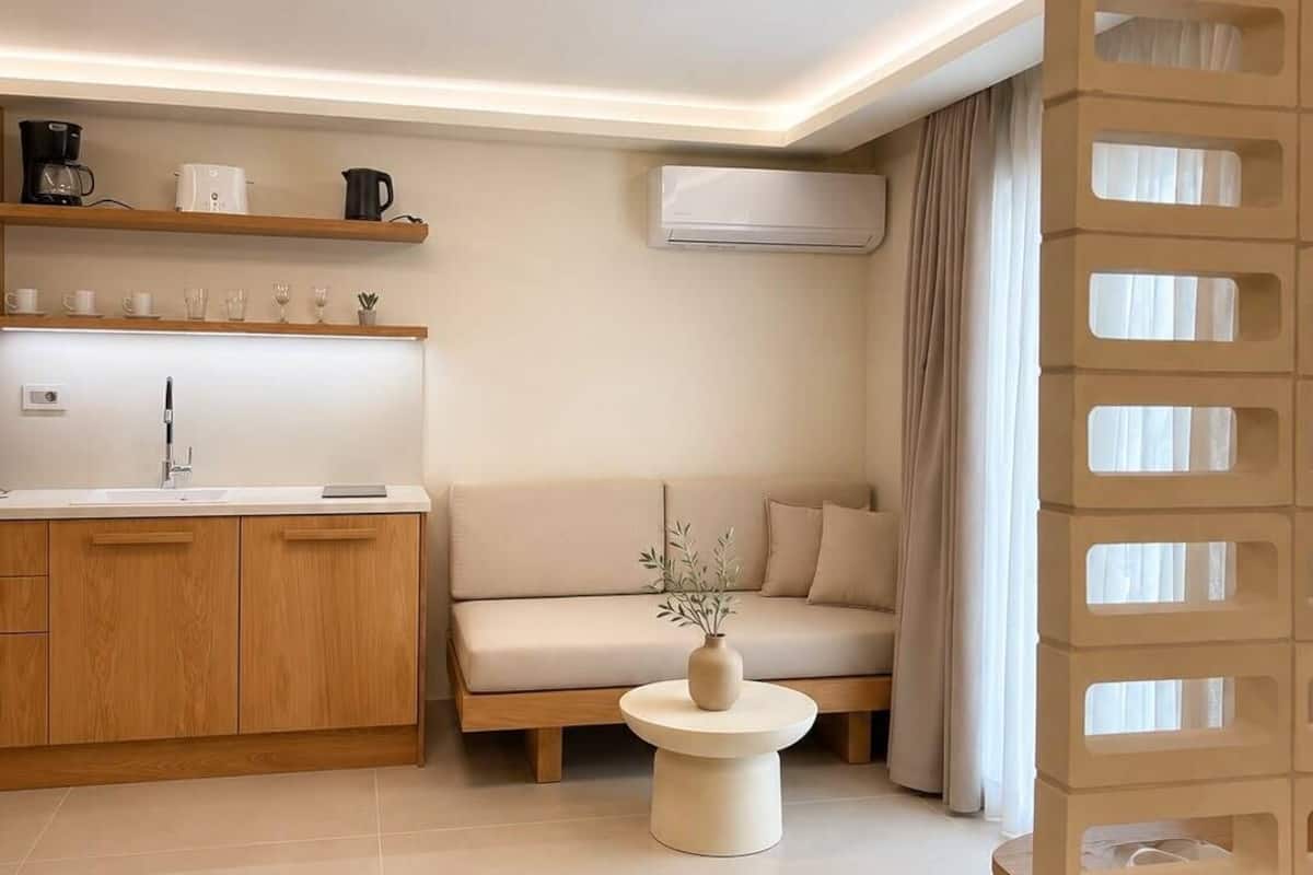 Ein modernes Wohnzimmer mit Sofa, Couchtisch und Küchenzeile mit Regalen.