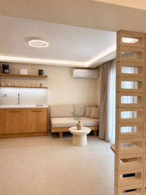 A modern living room with a sofa, coffee table, and kitchen area with shelves.