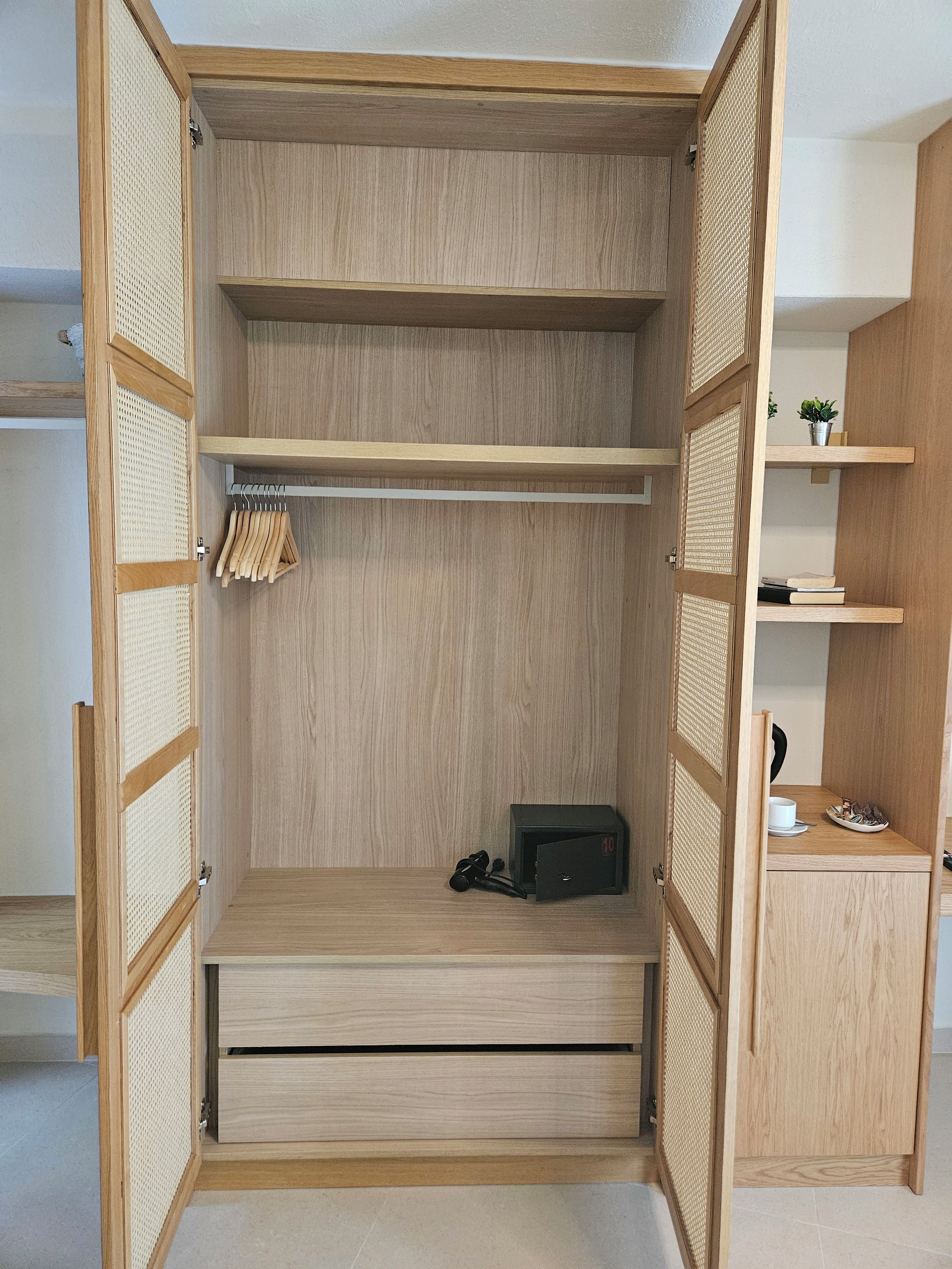 A wooden wardrobe with multiple compartments and a small shelf.