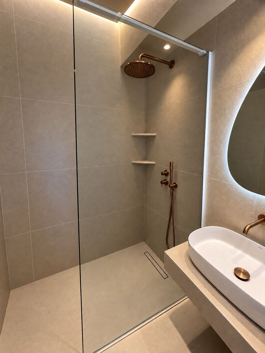 A modern bathroom with a glass-enclosed shower, a white sink, and a curved mirror.