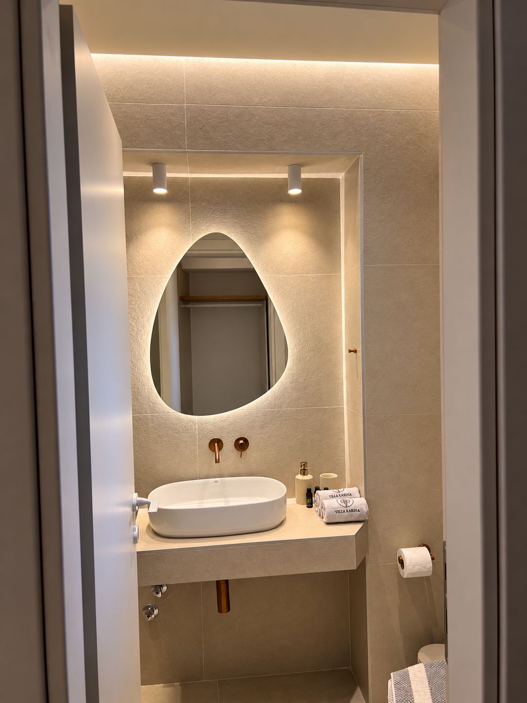 A modern bathroom with a round mirror, a sink, and a toilet.