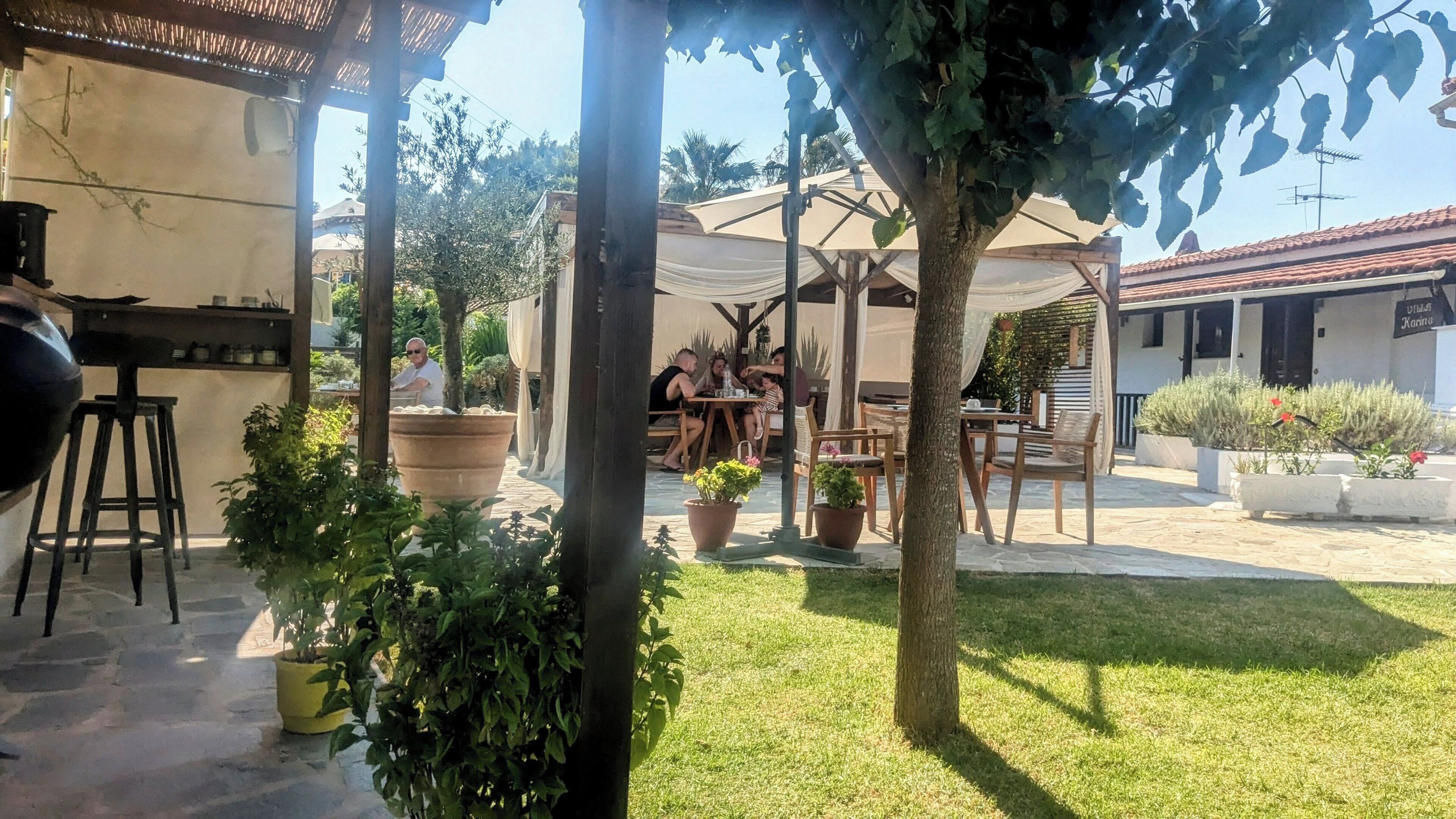 A patio area with outdoor seating, a grill, and potted plants.