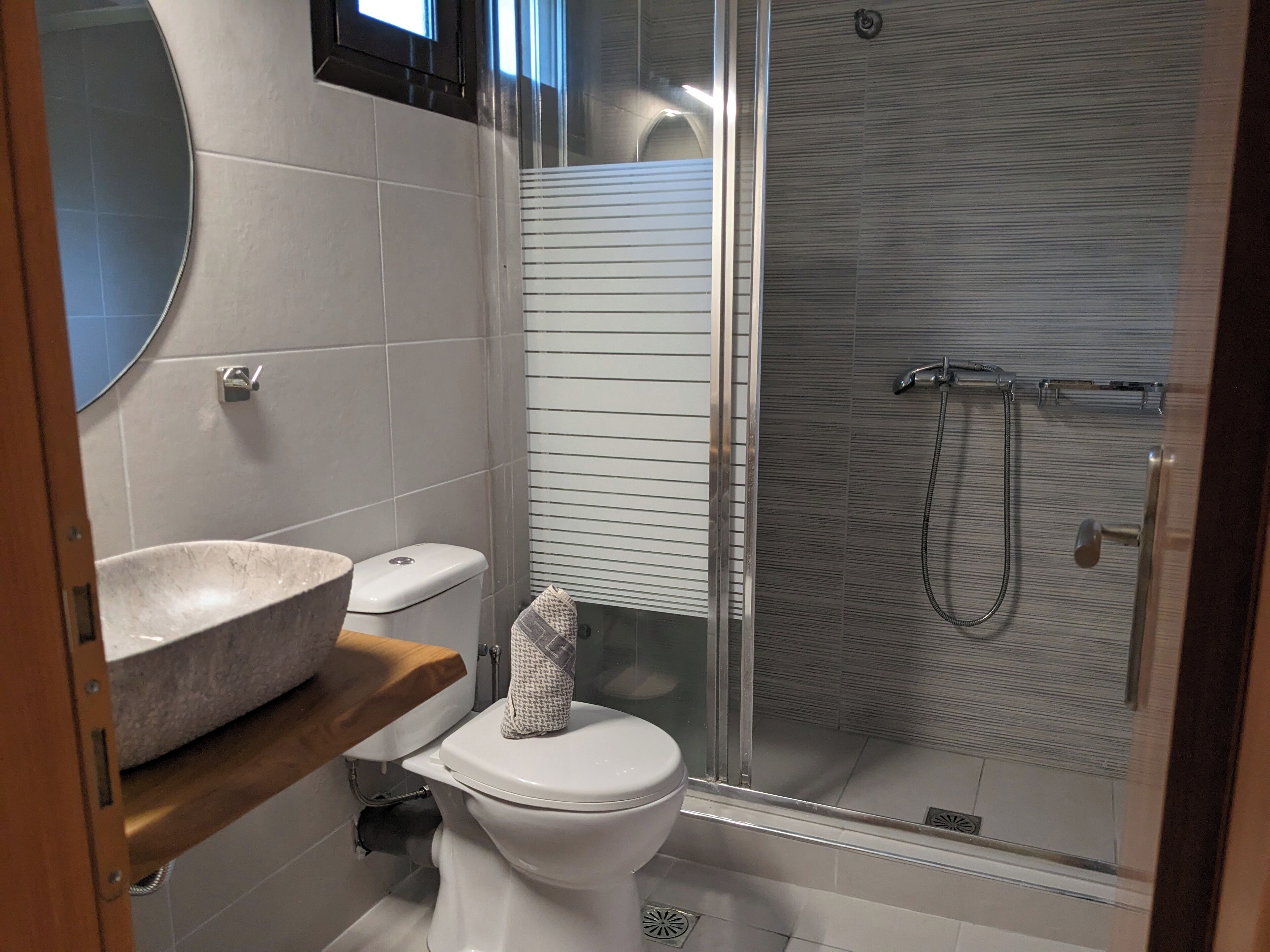 A modern bathroom with a large sink, toilet, and a glass-enclosed shower area.