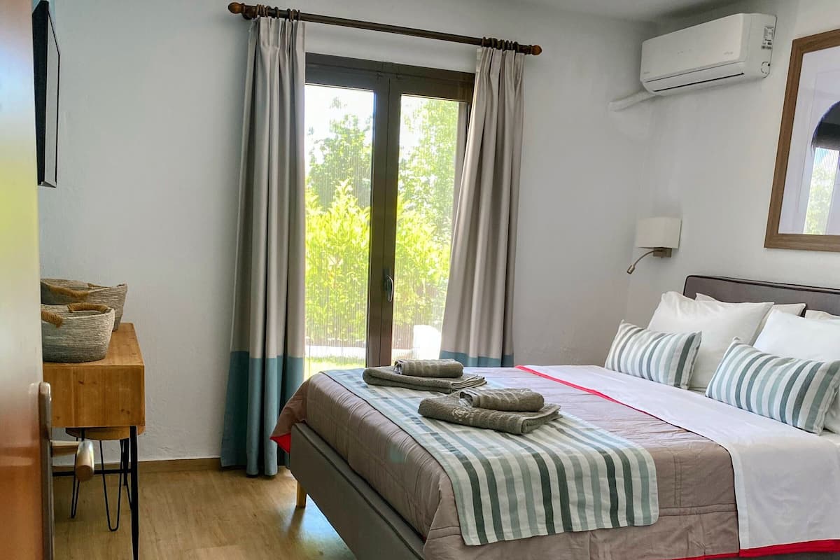 Ein Schlafzimmer mit einem Bett, einem Schreibtisch, einem Stuhl und einem Fenster mit Vorhängen.