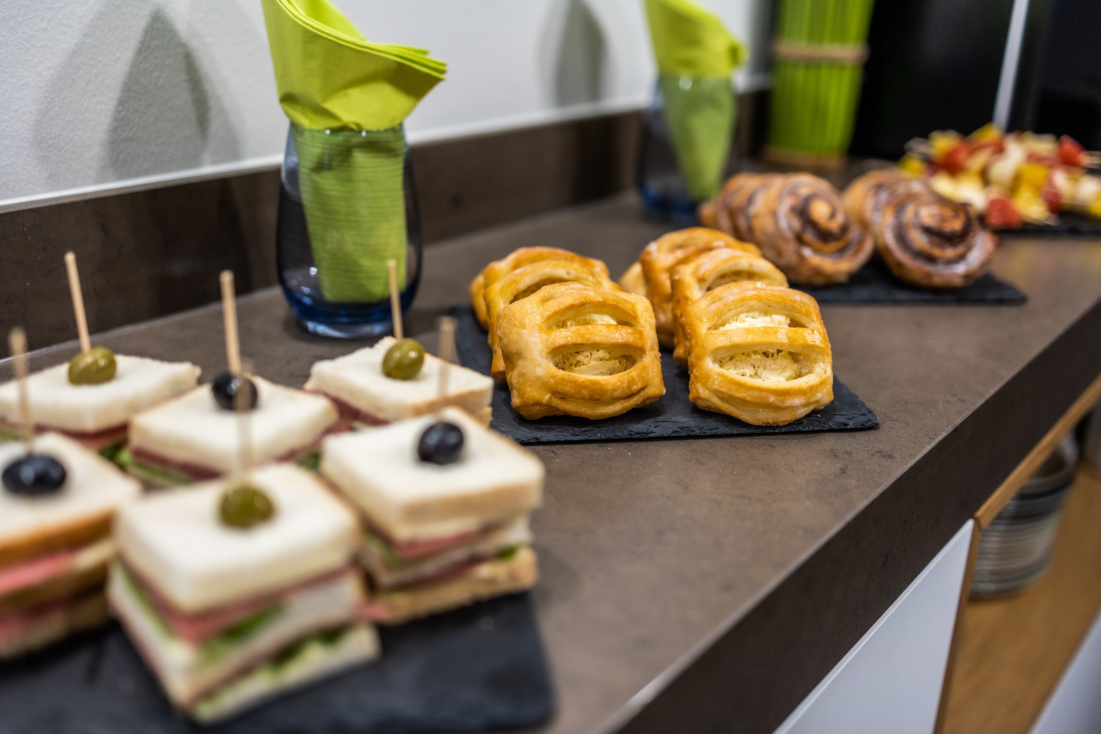 Taula de buffet amb entrepans, pastissos i broquetes de fruita.