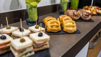 Ein Buffet mit Sandwiches, Gebäck und Obstspießen.