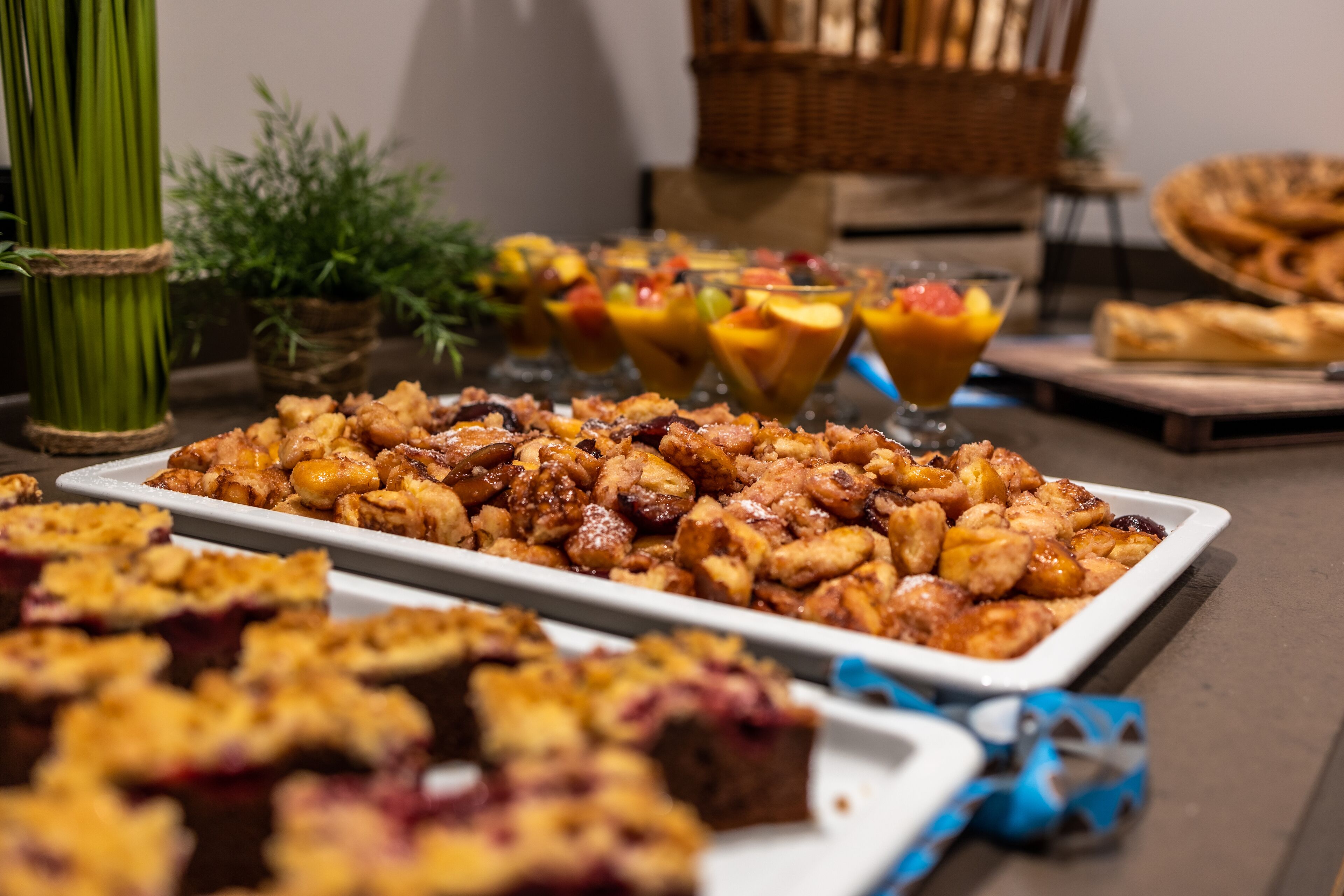 Ein Buffet mit verschiedenen Speisen, darunter eine große Auswahl an Backwaren und mehrere Obst-Parfaits.