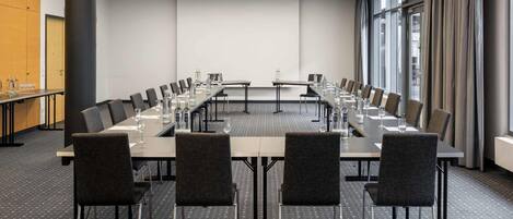 A conference room with a long table, multiple chairs, and a projector screen.