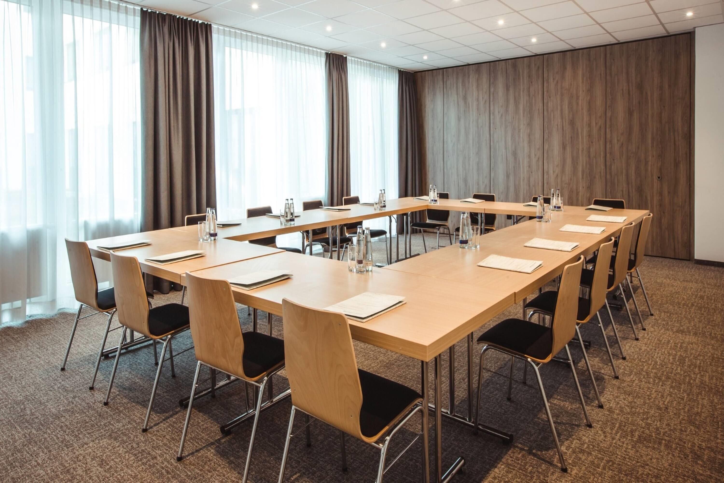 Ein Konferenzraum mit einem langen Tisch, Stühlen und Teppichboden.
