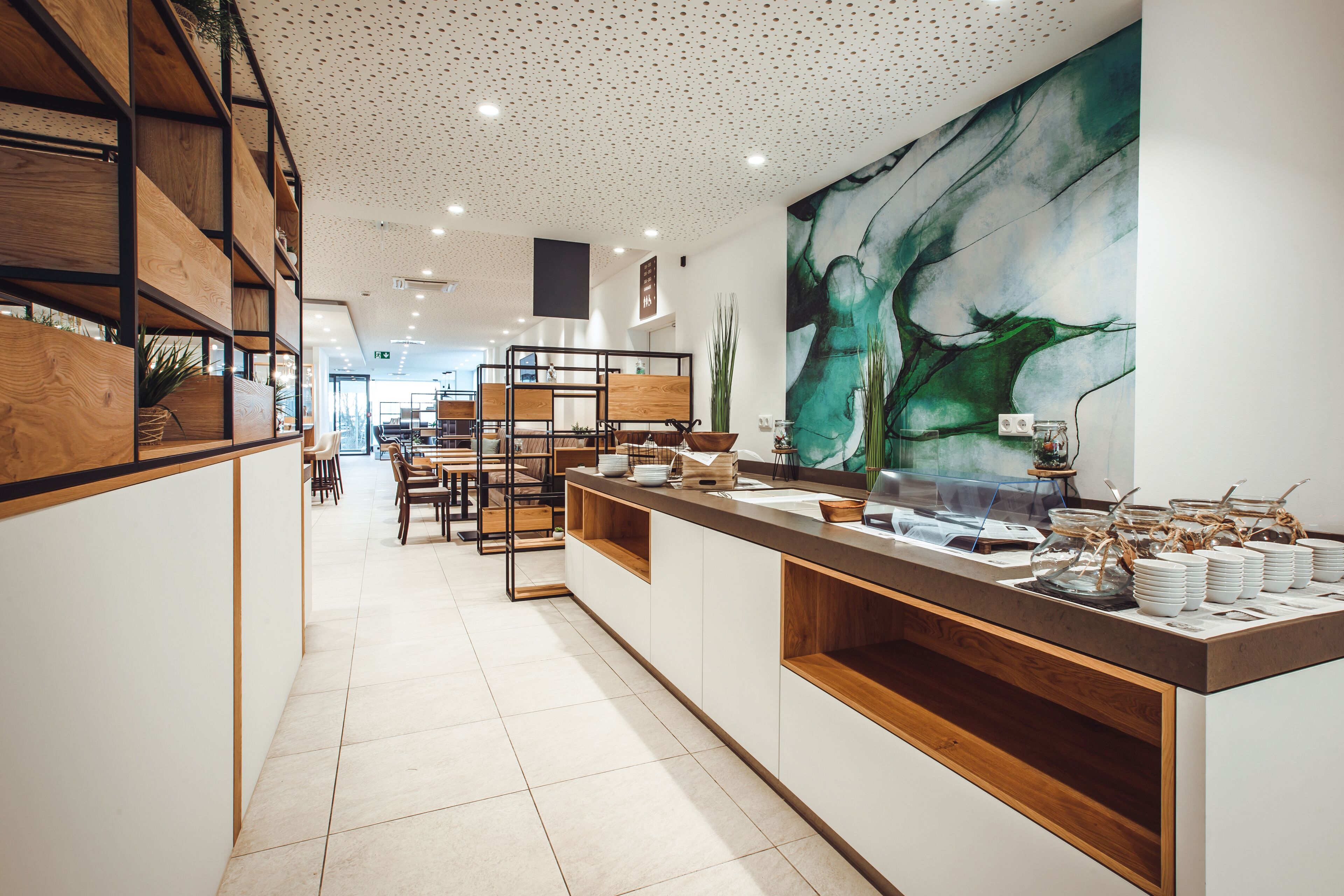 Un restaurante moderno con una barra alargada, estanterías de madera y un cuadro abstracto grande en la pared.