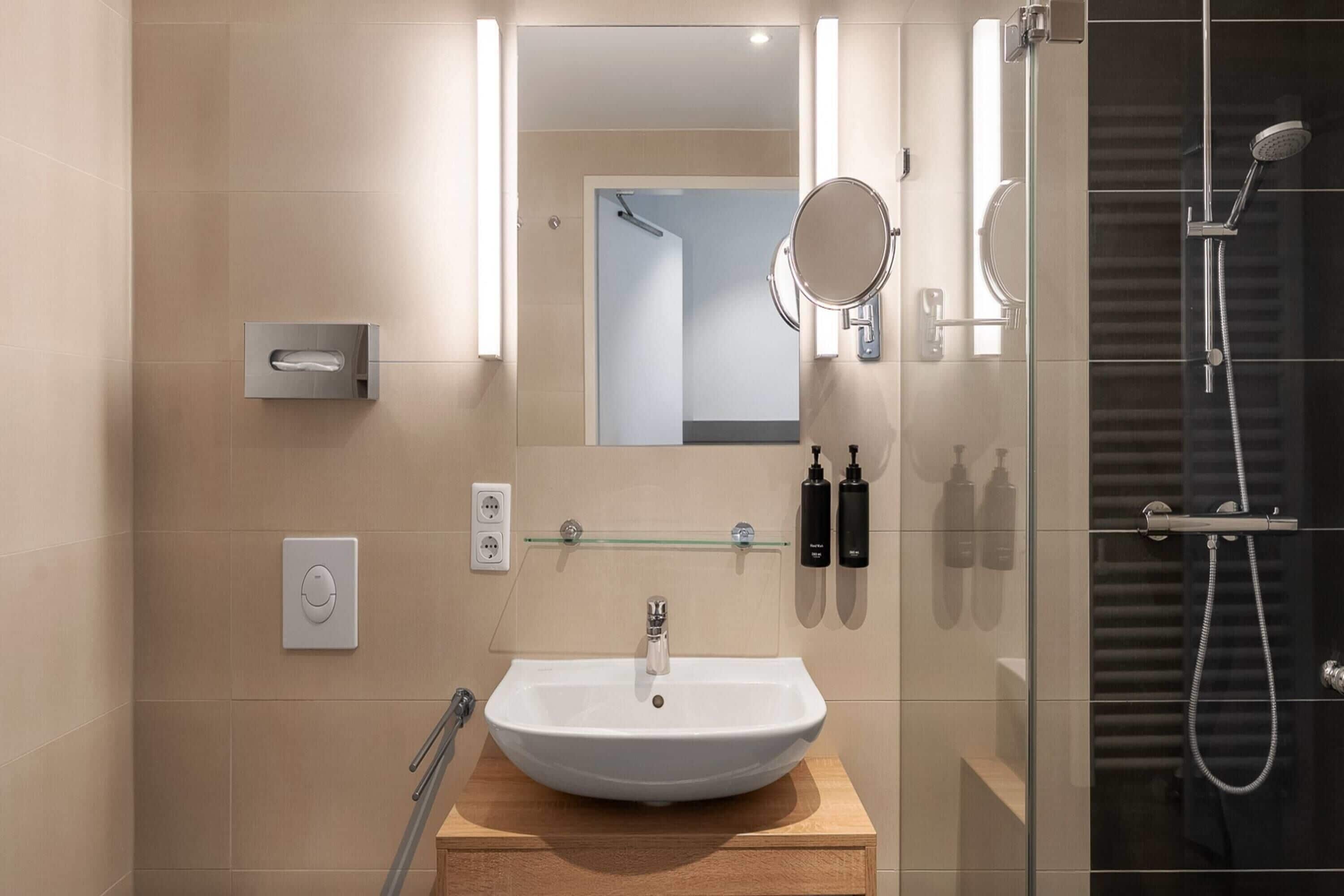 Ein modernes Badezimmer mit einem großen Waschbecken, einem Spiegel und einer Duschkabine aus Glas.